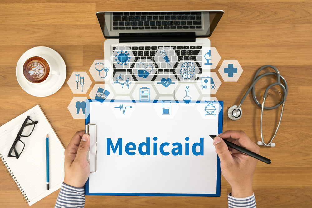 desk with laptop and a clipboard with medicaid on it