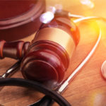 Gavel and stethoscope on wooden background, symbol photo for bungling and medical error