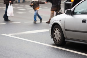 a mother and son pedestrians crossing in front of a silver vehicle