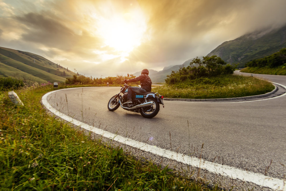 Motorcycle driver riding in Alpine landscape.