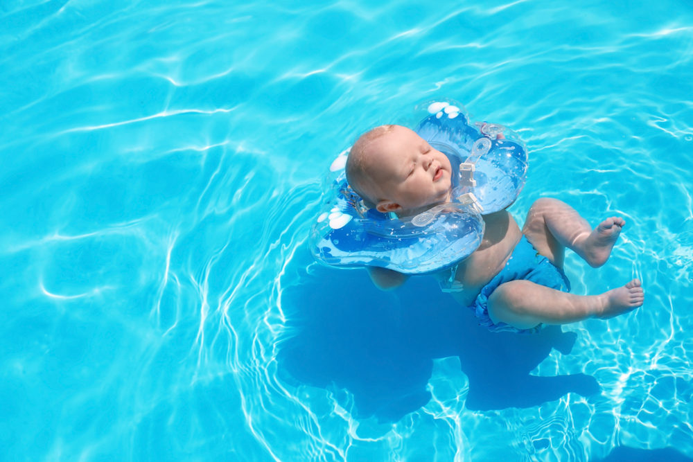 little baby with inflatable neck ring in swimming pool