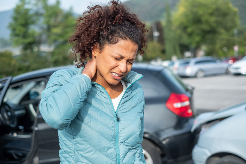 young woman holding her neck after being involved in a car accident