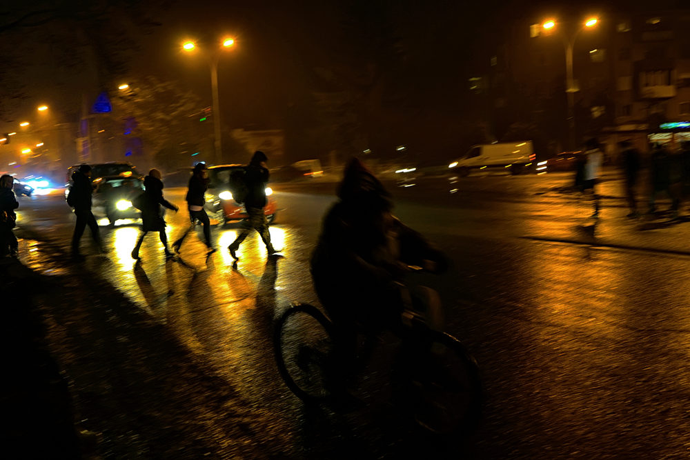 night time road with cars waiting for pedestrians to cross