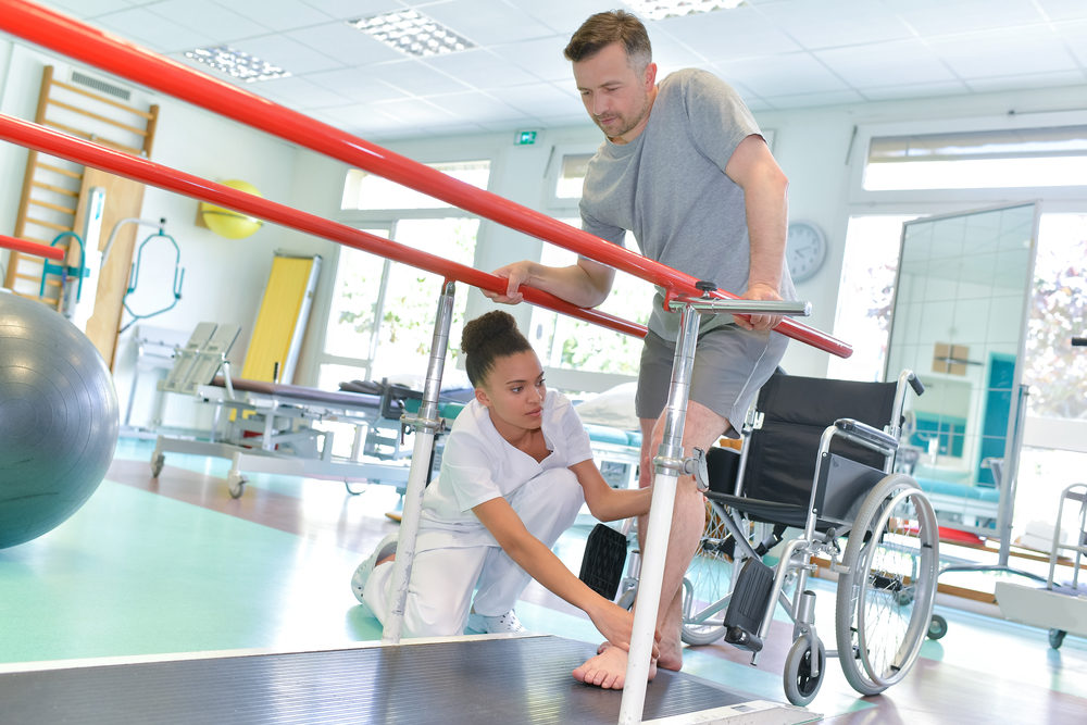 An occupational therapist helps a wheelchair-bound patient to walk