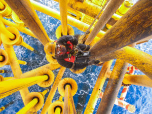Male worker rope access inspection of thickness offshore drill yellow oil and gas production petroleum pipeline