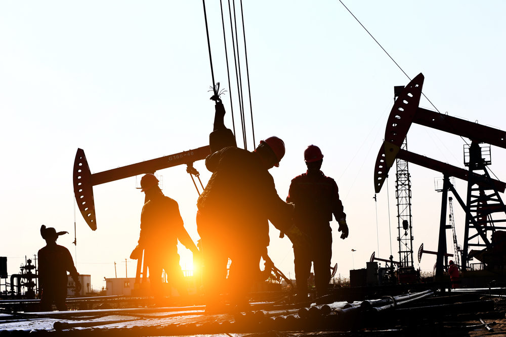 Oil workers at a rig  at sunset