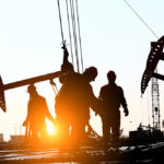 Oil workers at a rig  at sunset