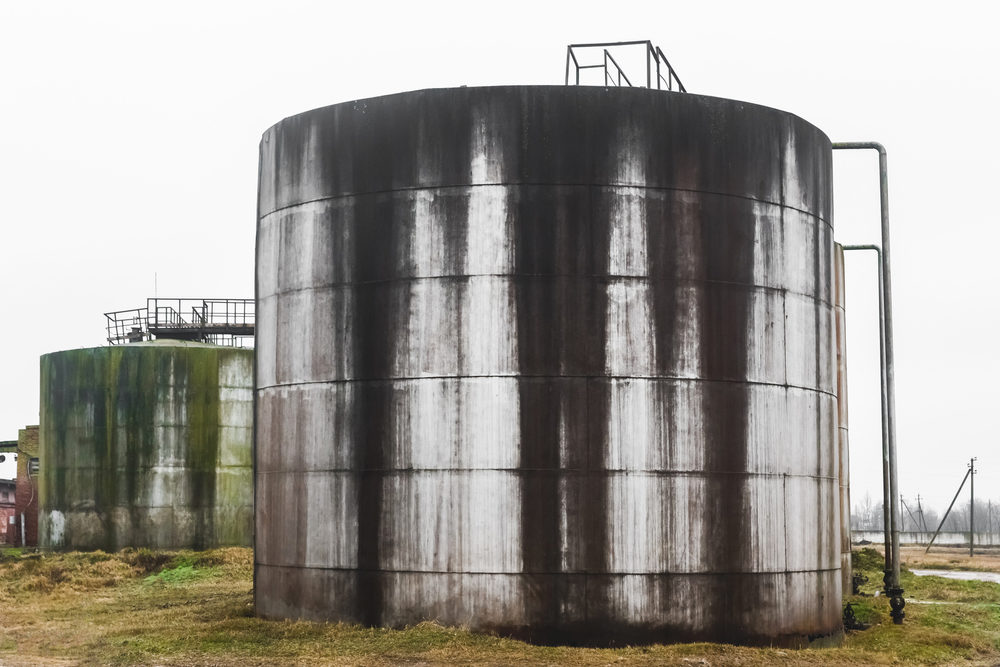 Old fuel oil tanks with smudges of fuel oil in an abandoned industrial plant