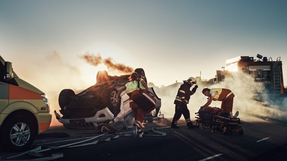 firefighters and paramedics tending to an injured person on stretcher after an overturned vehicle accident