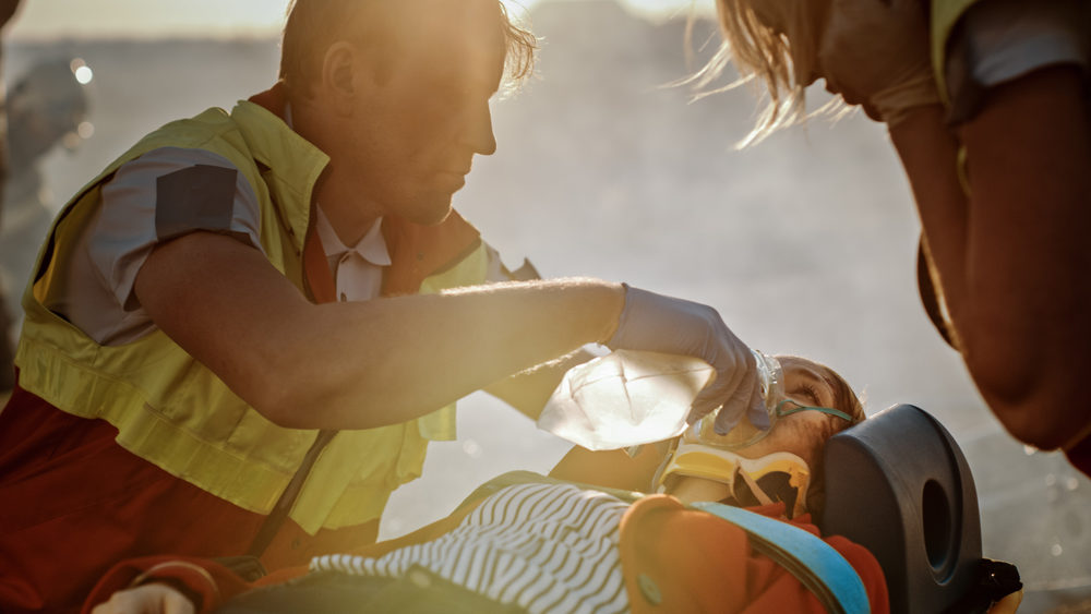 paramedics applying an oxygen mask to a female accident victim in a stretcher