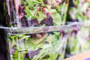 Macro closeup of mixed green salad in boxes on display