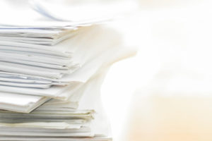 Large stack of white papers piled on a desk