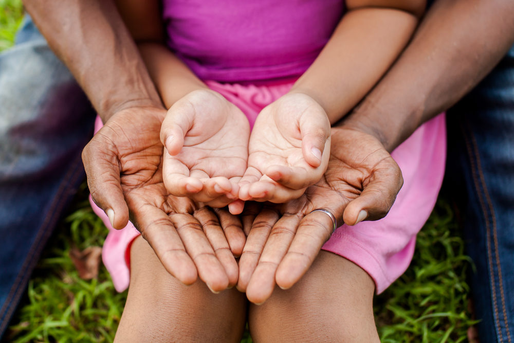 african american daughter laying her hands on her fathers palm side up