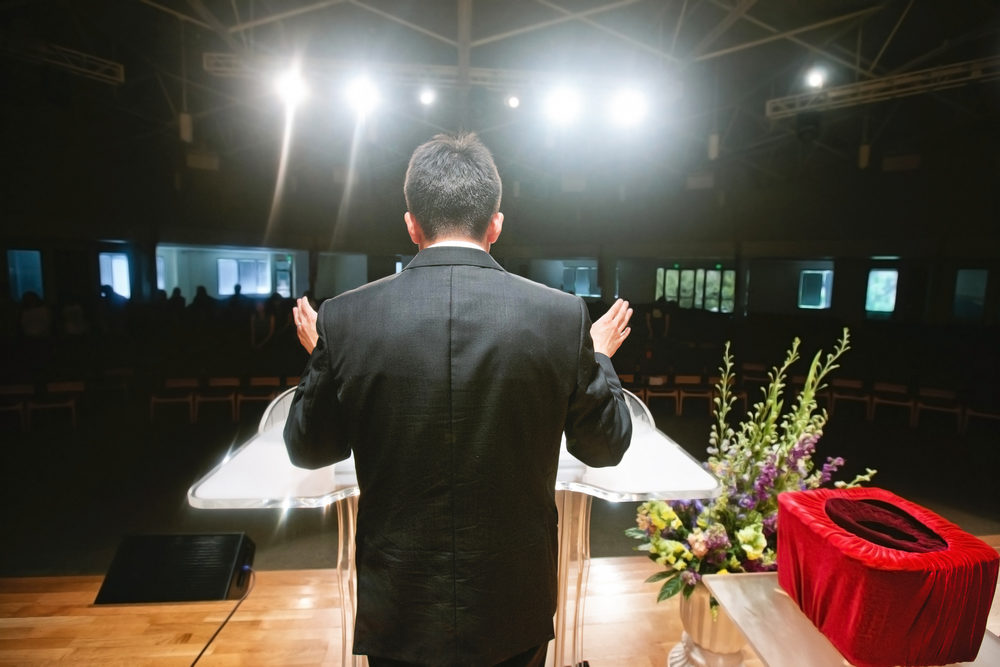 pastor praying for congregation during a service