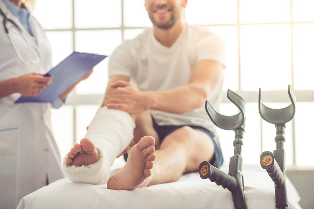 female doctor with a male patient with a broken leg on an exam table in office