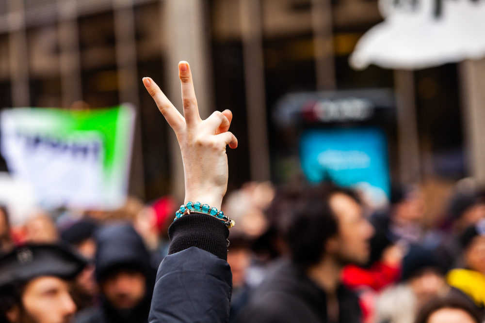 Protester female holding up a peace sign among a crowd of activists