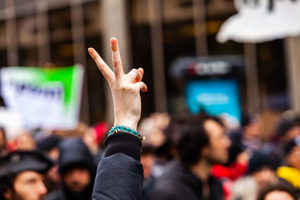 Buffalo’s Civil Justice Community Calls for Change Protester female holding up a peace sign among a crowd of activists