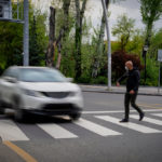 Pedestrian walking on zebra crossing and a driving car failing to stop in blurred motion.