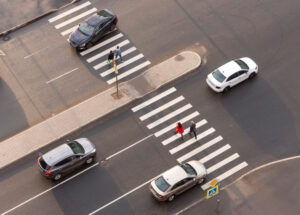 pedestrians and cars passing through a crosswalk