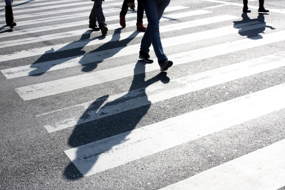 shadows of pedestrians in a crosswalk on a road