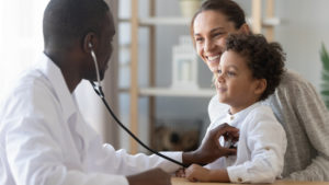 African male pediatrician hold stethoscope exam child boy patient visit doctor with mother,