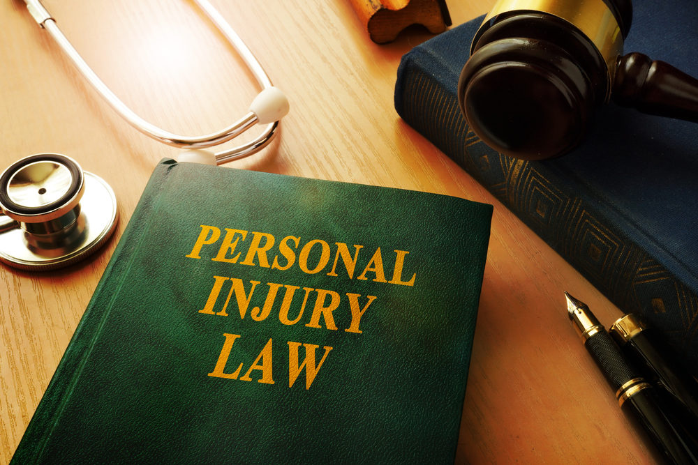 A book titled "PERSONAL INJURY LAW" sits on a desk with a gavel and stethoscope