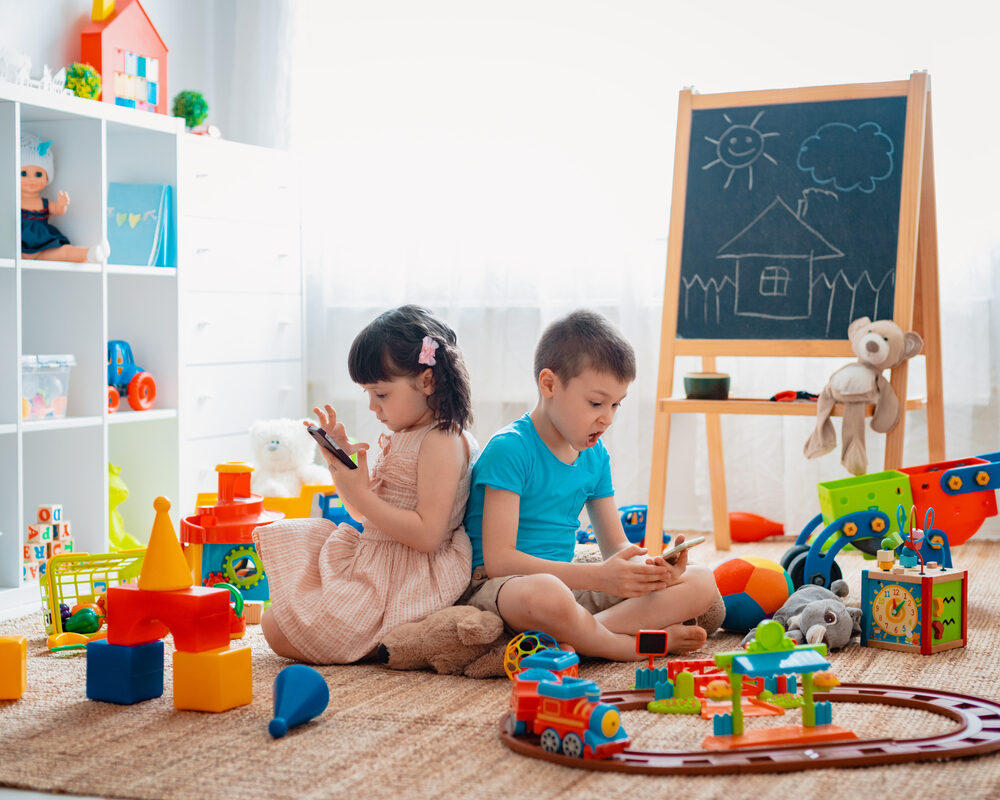 Grayslake Man, Jose Real, Arrested for Over 1,000 Child Pornography Videos at Daycare Home Siblings children brother and sister sit on the floor of the house in the children's play room with smartphones, detached from the scattered toys.