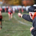 an older man pointing at girls cross country race