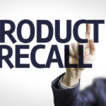 Business man pointing to transparent board with text: Product Recall