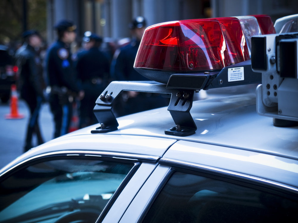 Red lights atop a police cruiser, with officers visible in the background