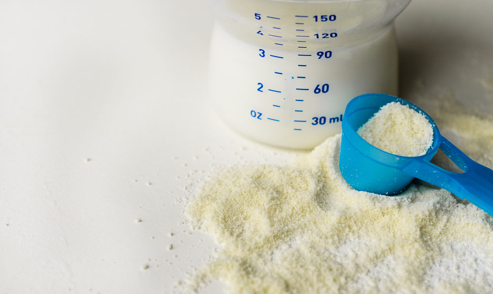 powder milk for baby and blue spoon on light background