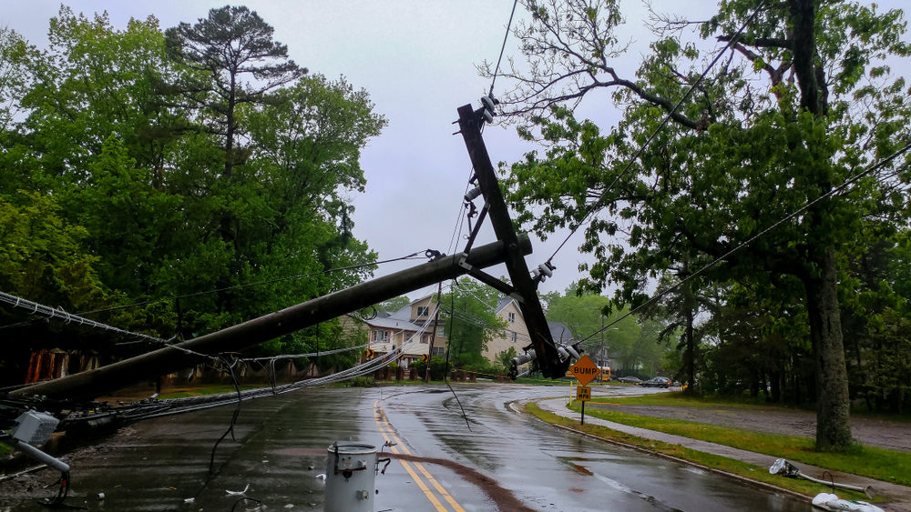 Beware of Downed Wires After a Car Crash in Detroit electric power pole laying across a road after being downed by a hurricane