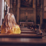 Young woman praying and meditating in church.