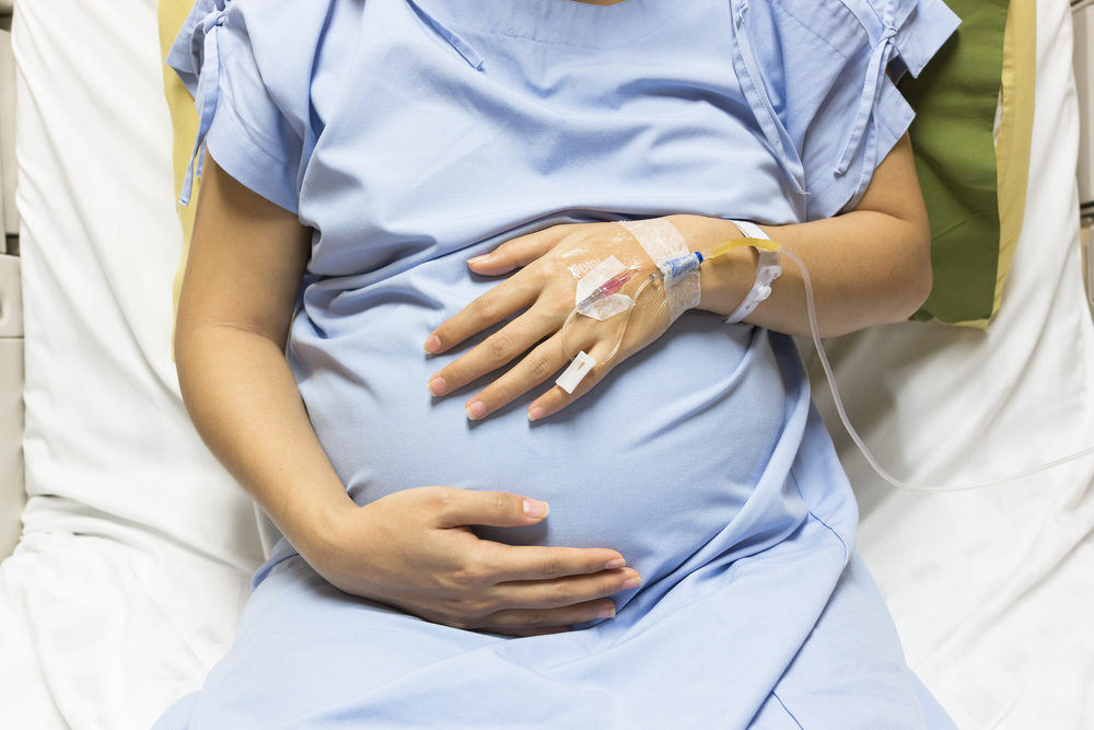 Asian Pregnant Woman patient is on drip receiving a saline solution on bed VIP room at hospital, 