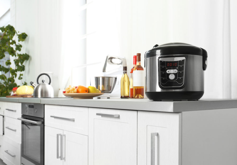 Modern multi cooker and products on table in kitchen.