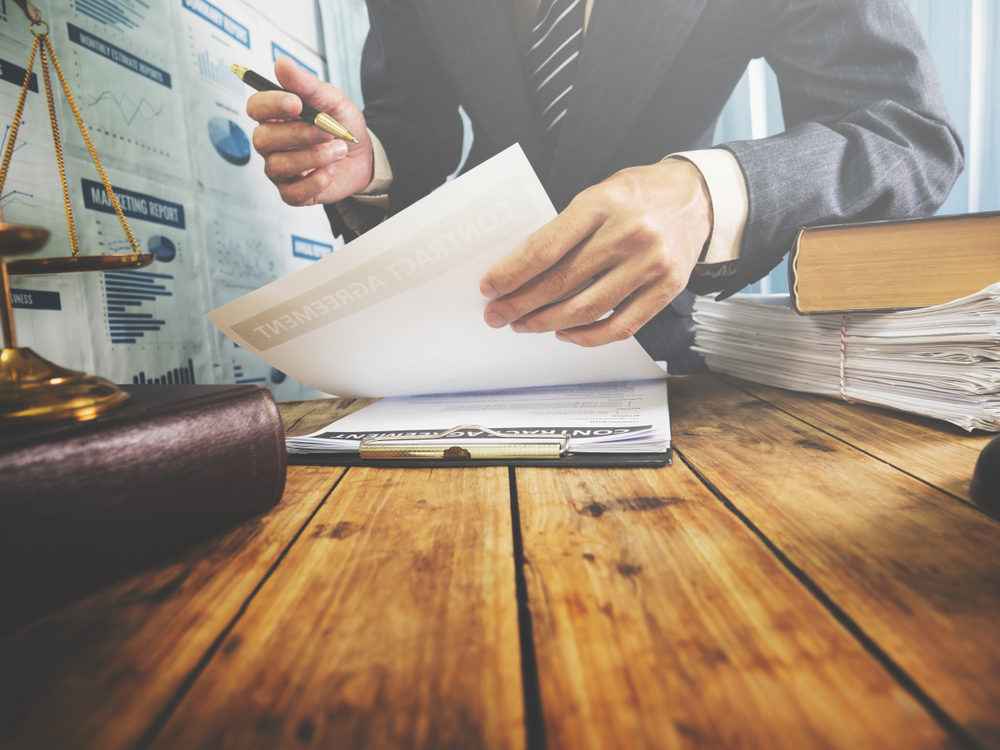 lawyer looking over agreement with pen in hand at desk