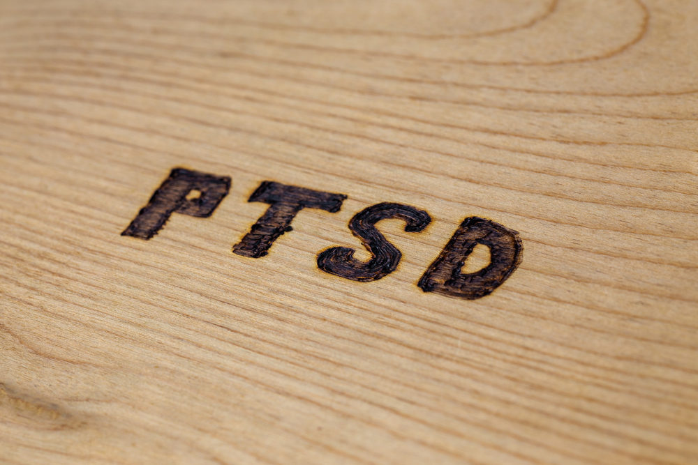 an abbreviation PTSD - post traumatic stress disorder - burned by hand on flat wooden board in diagonal composition