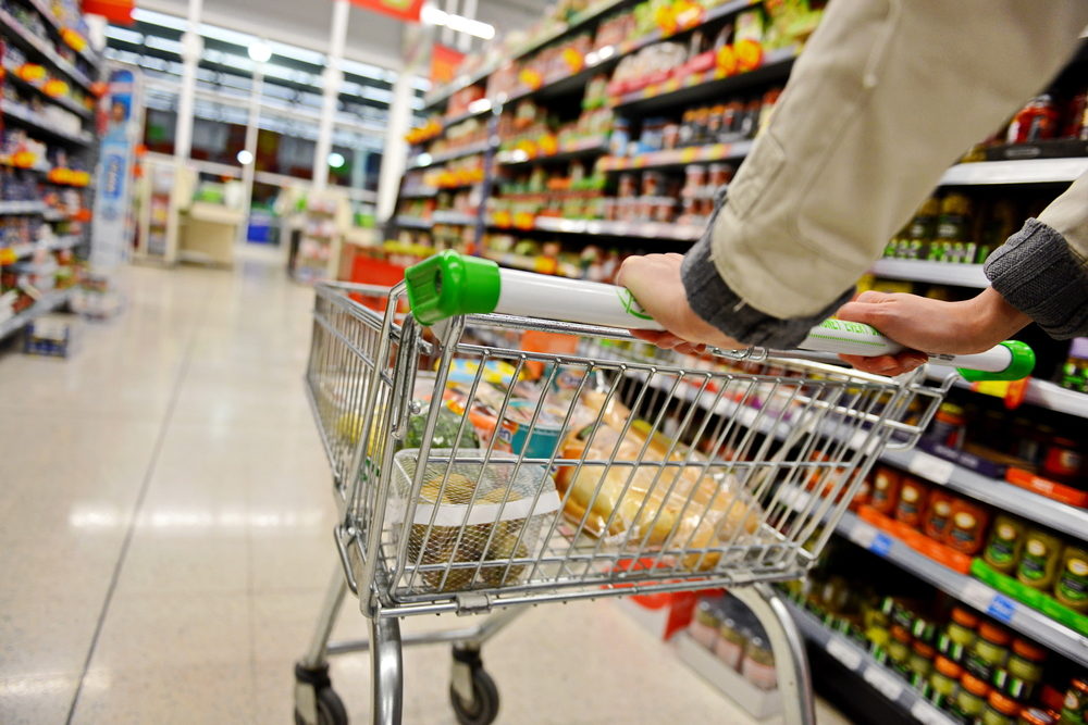 A shopping cart being pushed down a grocery aisle by an unseen person