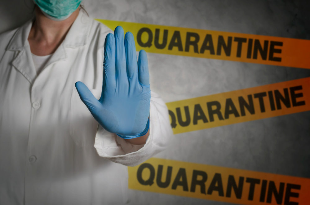Quarantine tape behind a healthcare worker holding up their gloved hand