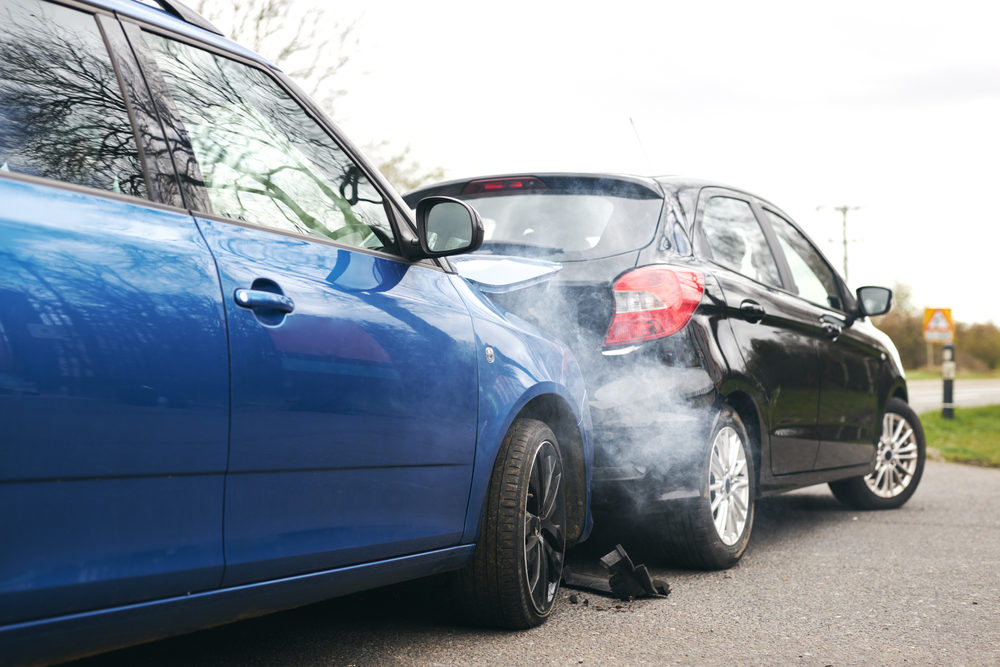 Two cars involved in traffic accident on side of the road with damage to fender