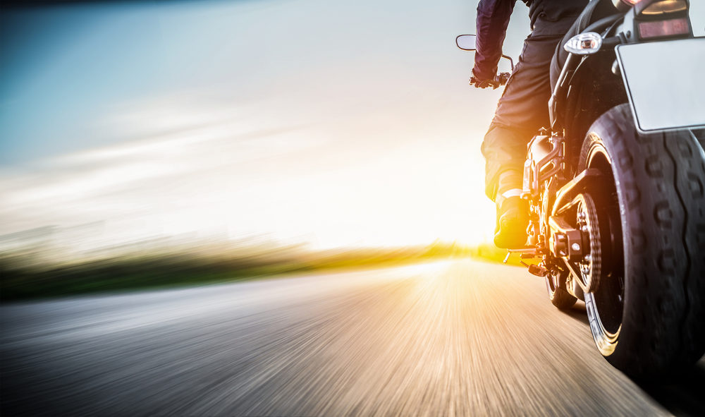 rear view of motorcycle on roadway driving towards sunset