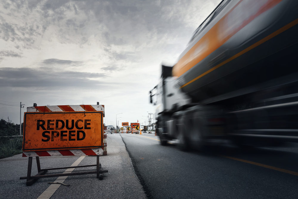Semi-Truck Driver With BAL Twice the Limit Crashes Into St. Ignatius College Prep School Bus Injuring 16 in Warsaw, IN Reduce speed road sign on a countryside road with blurry truck