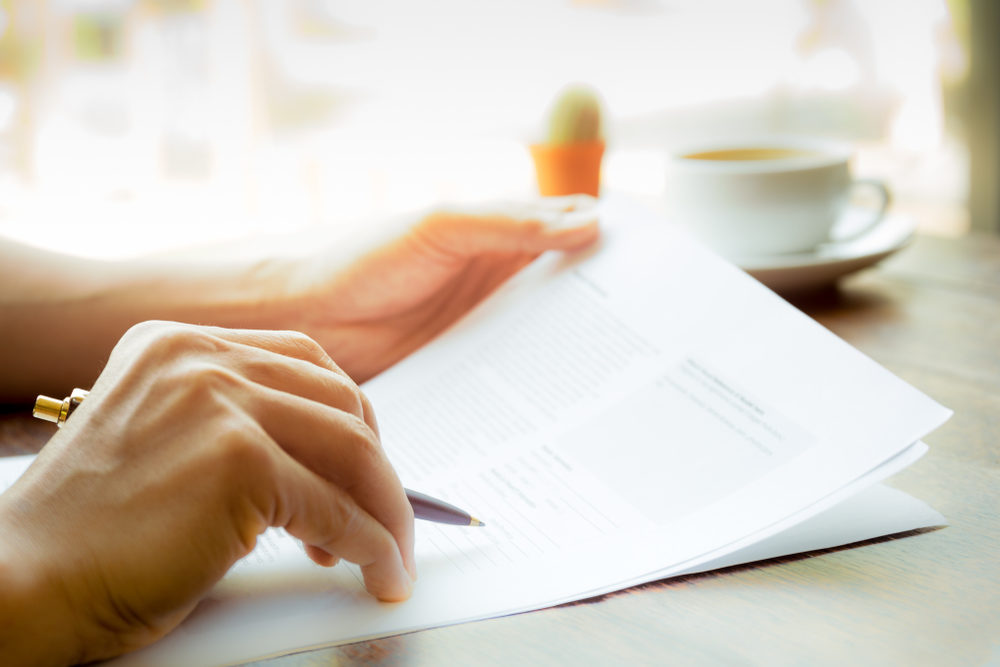 A person with pen in hand reviewing some paperwork