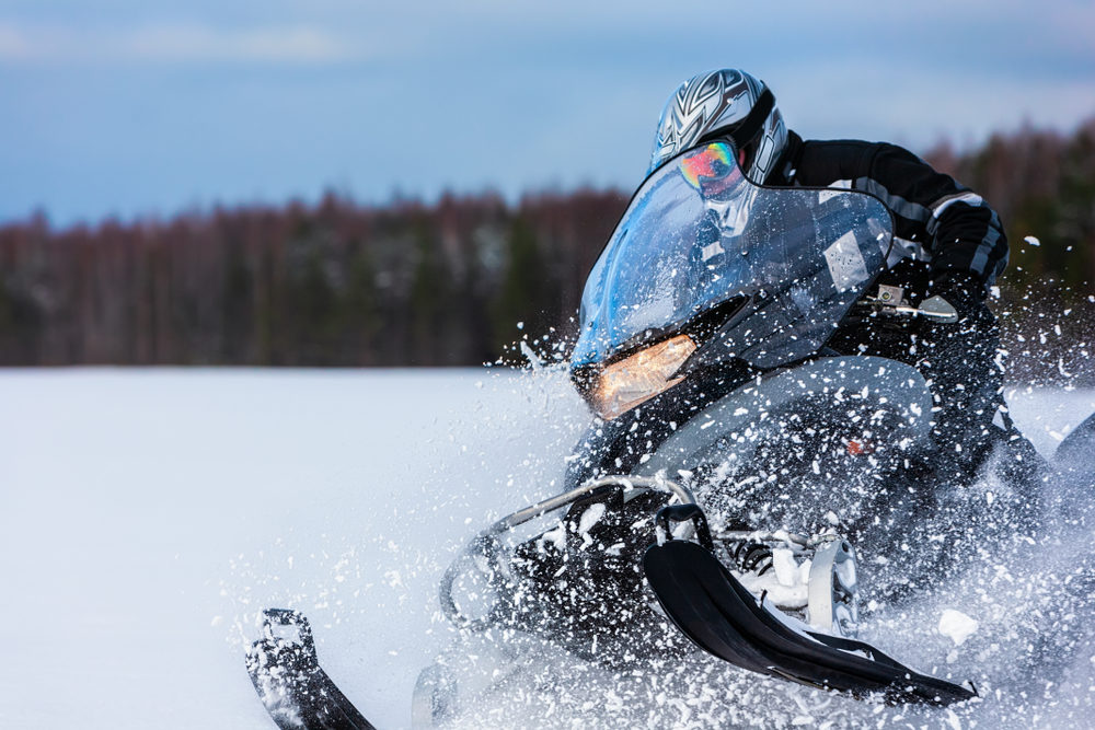 In deep snowdrift snowmobile rider driving fast.