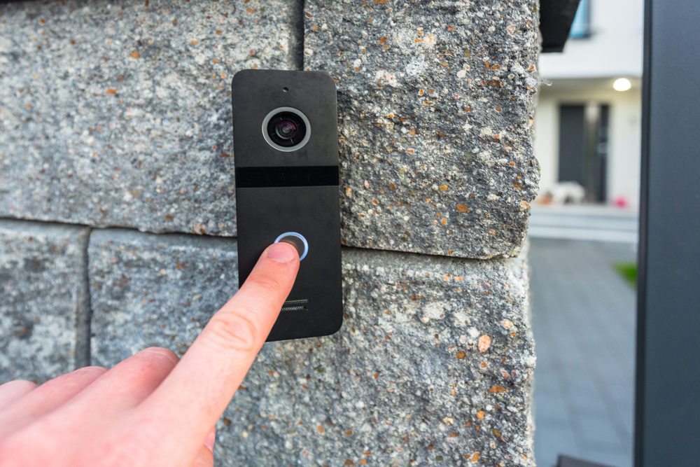 Hand pressing button of video intercom mounted on the stone wall