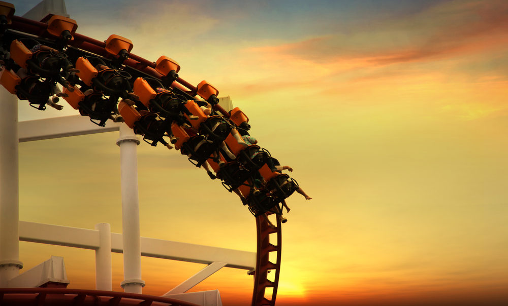 People on a roller coaster against a sunset background