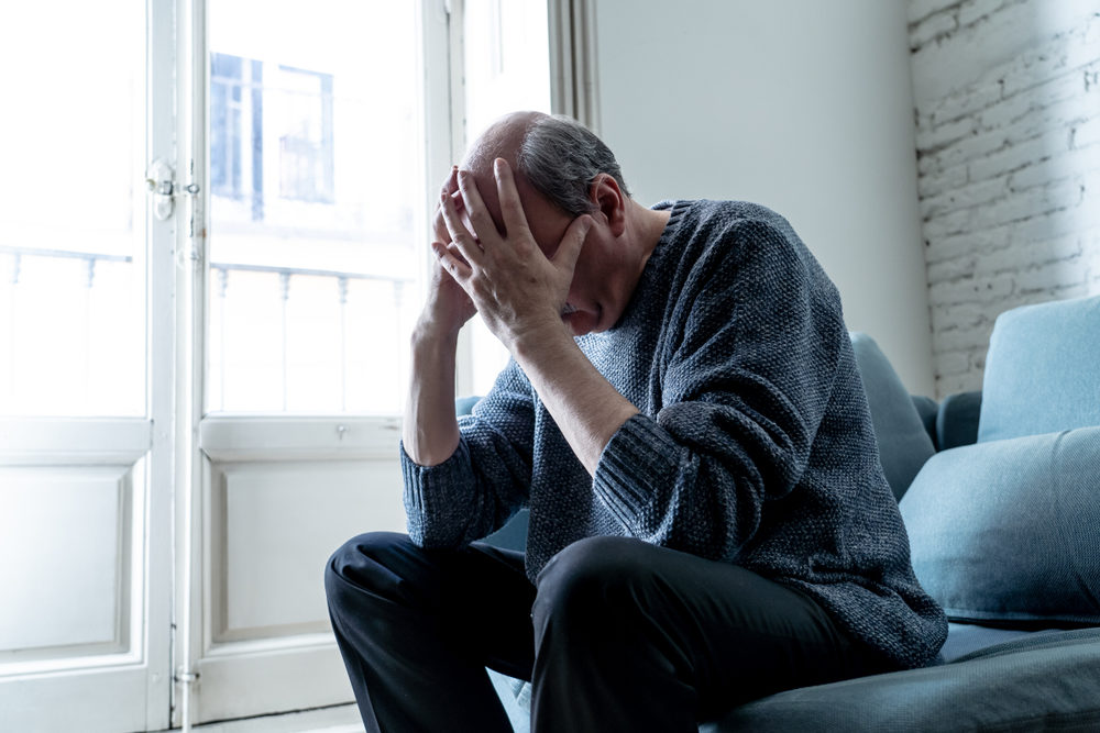 Overwhelmed older man holding his head in his hands