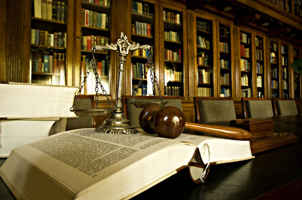 Scales of justice and gavel laying on law book in library