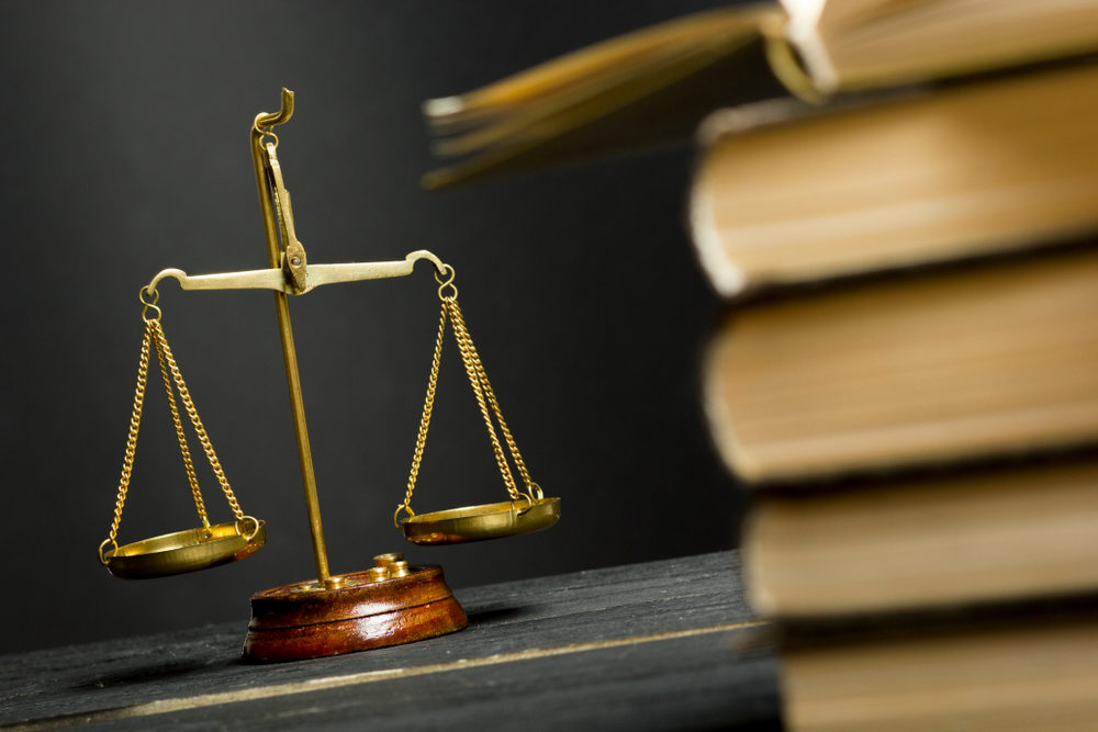 law books in forefront of table with scales of justice in background