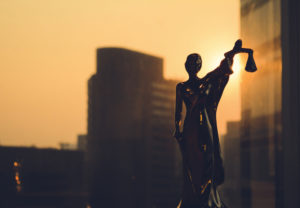  Statuette of the goddess of justice with cityscape at sunset behind